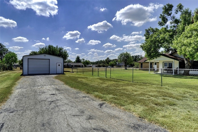 view of yard featuring a garage, an outbuilding, driveway, and fence