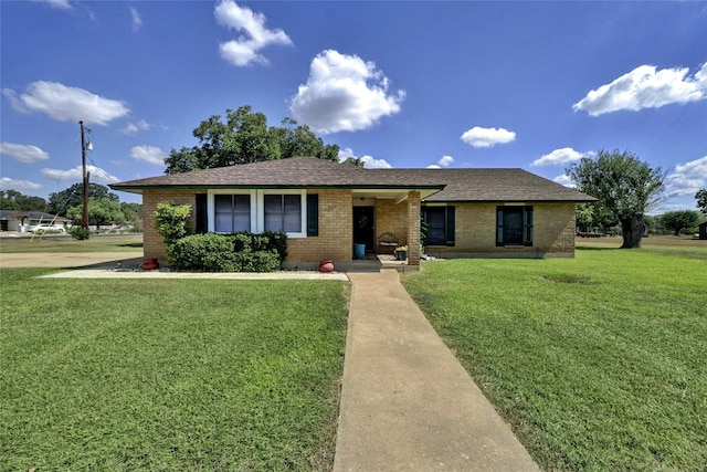 single story home with brick siding, a front yard, and a shingled roof