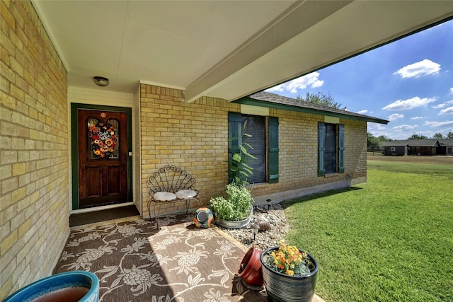 property entrance with a lawn and brick siding