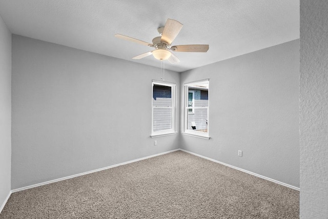 spare room with baseboards, a ceiling fan, a textured wall, a textured ceiling, and carpet flooring