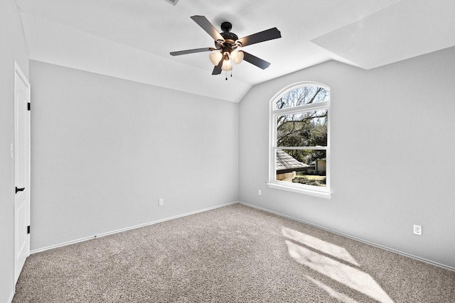 spare room featuring a ceiling fan, carpet, vaulted ceiling, and baseboards