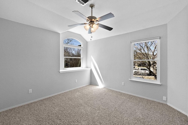 carpeted empty room with ceiling fan, visible vents, vaulted ceiling, and baseboards