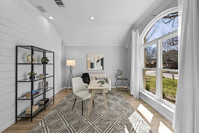 office space with baseboards, visible vents, vaulted ceiling, and light wood finished floors