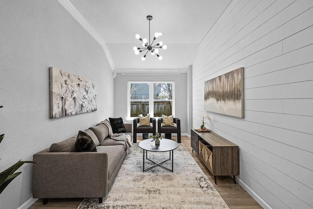 living room with a notable chandelier, ornamental molding, wood finished floors, and baseboards