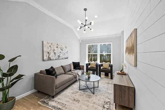 living area featuring lofted ceiling, a chandelier, wood finished floors, baseboards, and crown molding