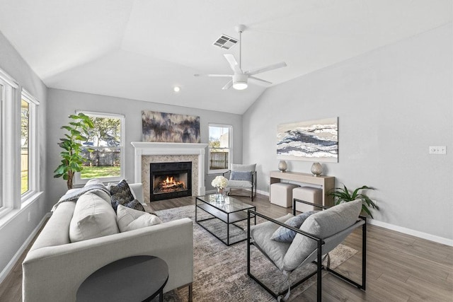 living area with lofted ceiling, plenty of natural light, visible vents, and wood finished floors