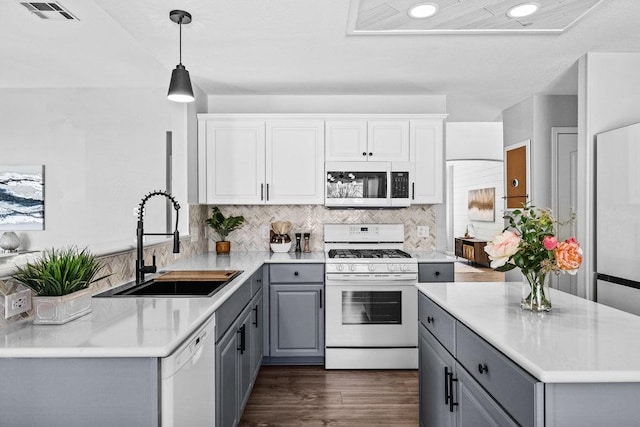 kitchen featuring white appliances, tasteful backsplash, visible vents, gray cabinets, and a sink