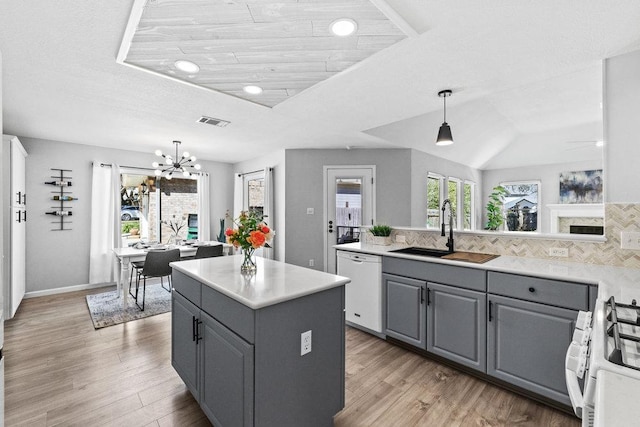 kitchen with light wood finished floors, gray cabinets, visible vents, a sink, and white appliances