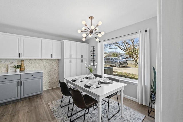 dining room featuring baseboards, dark wood finished floors, and a notable chandelier