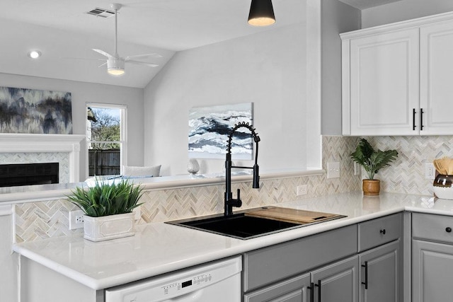 kitchen featuring white dishwasher, a fireplace, a sink, visible vents, and open floor plan