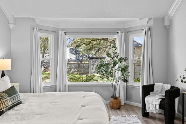 bedroom with crown molding, baseboards, and wood finished floors