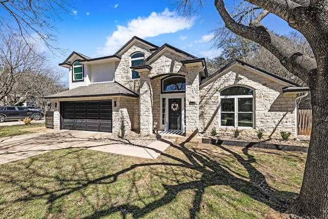 french country home with stone siding, an attached garage, driveway, and a front yard