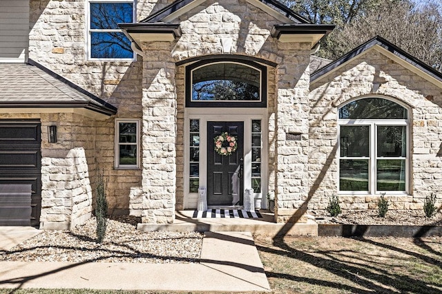 entrance to property with stone siding and an attached garage