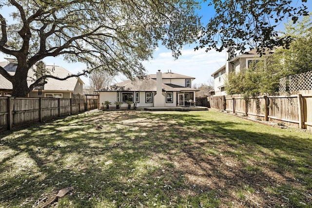 back of property with a fenced backyard, a deck, and a yard