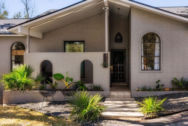 view of exterior entry with a shingled roof and stucco siding