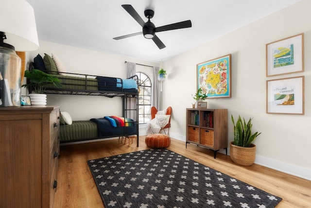 bedroom with a ceiling fan, baseboards, and wood finished floors