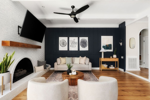 living area with visible vents, arched walkways, beam ceiling, and wood finished floors