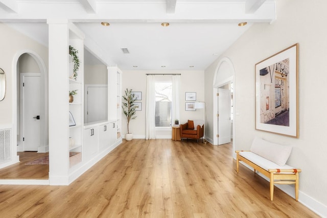 unfurnished room featuring light wood-type flooring, visible vents, baseboards, and arched walkways