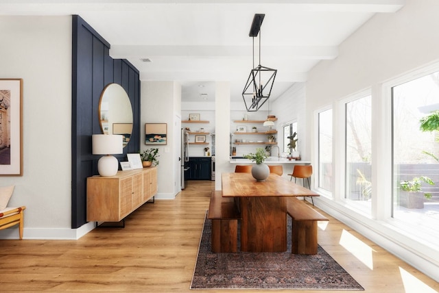 dining space featuring light wood finished floors, visible vents, an inviting chandelier, beamed ceiling, and baseboards