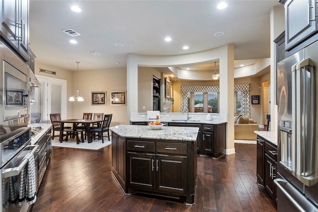 2717 Rain Song Dr, Leander, TX 78641 - kitchen featuring appliances with stainless steel finishes, a sink, dark brown cabinetry, hanging light fixtures, and dark wood finished floors