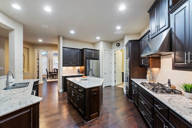 2717 Rain Song Dr, Leander, TX 78641 - kitchen with under cabinet range hood, a sink, appliances with stainless steel finishes, a kitchen island, and dark wood-style flooring