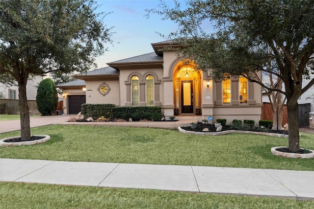 mediterranean / spanish-style home with driveway, a front yard, fence, and stucco siding