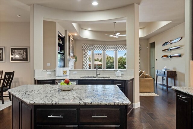 2717 Rain Song Dr, Leander, TX 78641 - kitchen with a sink, a ceiling fan, light stone counters, dark wood-style flooring, and a tray ceiling