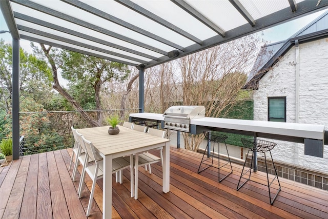 wooden terrace featuring outdoor dining area, outdoor dry bar, grilling area, and exterior kitchen