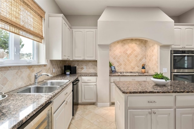 kitchen with light tile patterned flooring, a sink, white cabinets, appliances with stainless steel finishes, and backsplash