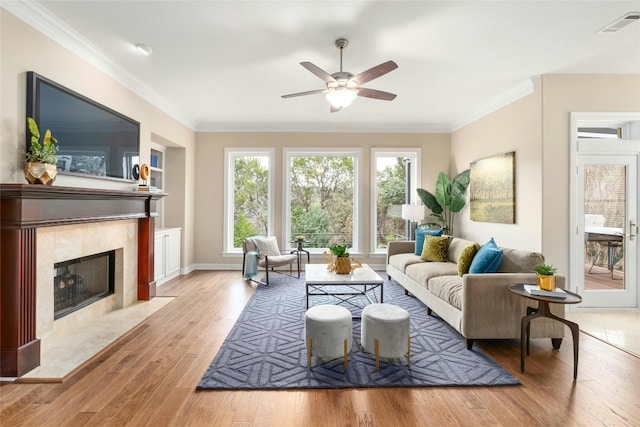 living room featuring built in features, crown molding, visible vents, a high end fireplace, and wood finished floors