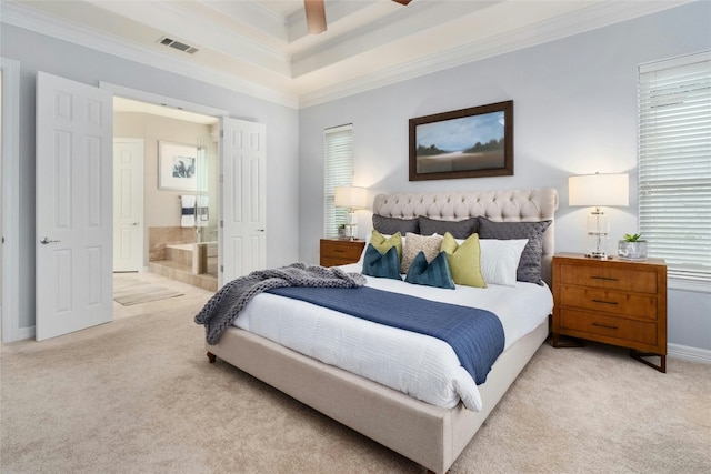 carpeted bedroom with baseboards, visible vents, a raised ceiling, ornamental molding, and ensuite bathroom