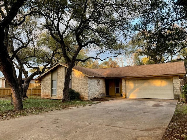 view of front of property with a garage, concrete driveway, stone siding, and fence