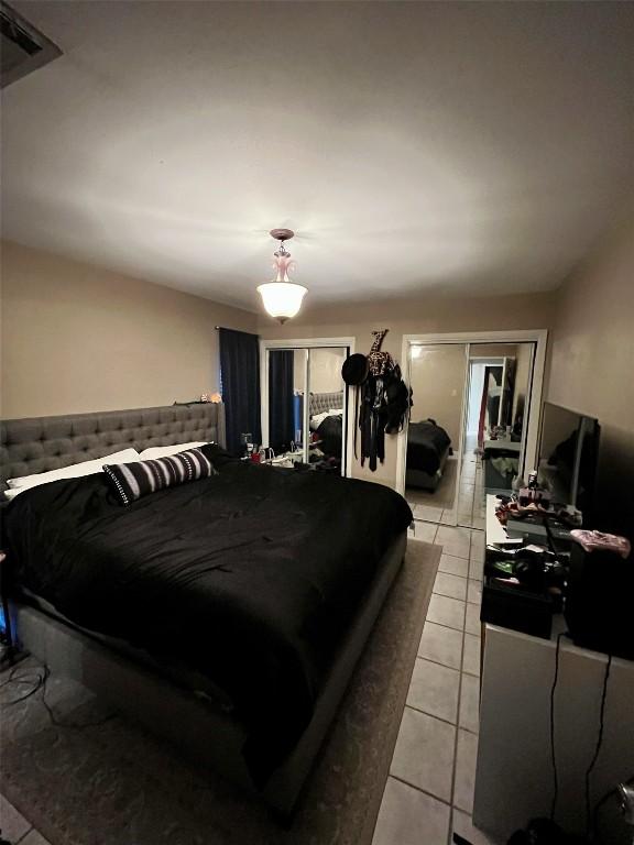 bedroom featuring light tile patterned floors and multiple closets