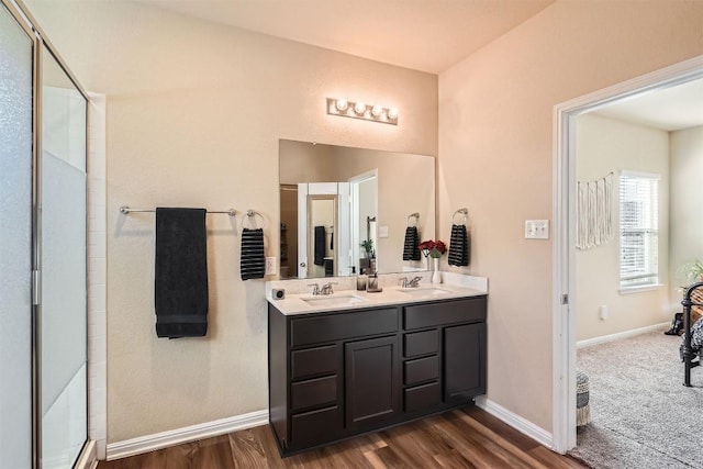 bathroom featuring double vanity, baseboards, a sink, and a shower with shower door