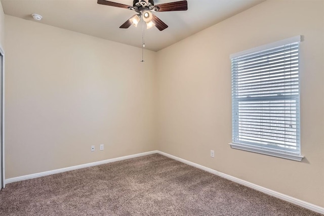 carpeted spare room with a ceiling fan and baseboards