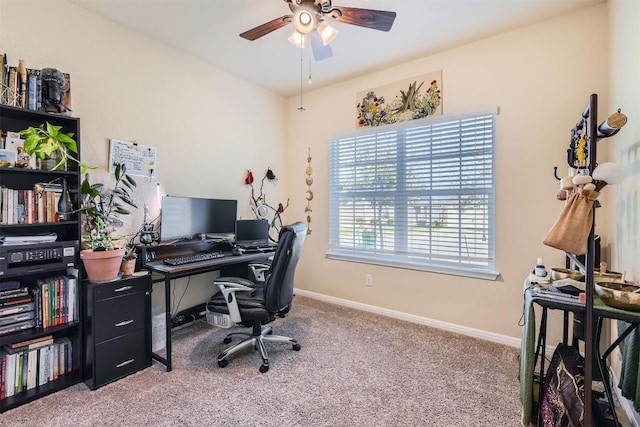 carpeted office space featuring ceiling fan and baseboards