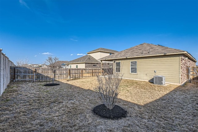 rear view of house with a fenced backyard, cooling unit, and a lawn