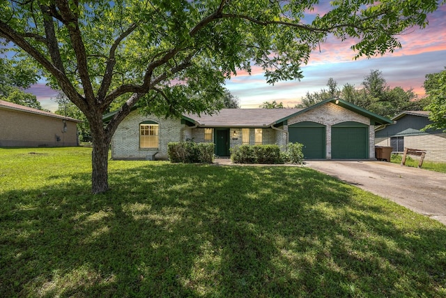 ranch-style home featuring a garage, concrete driveway, brick siding, and a front lawn