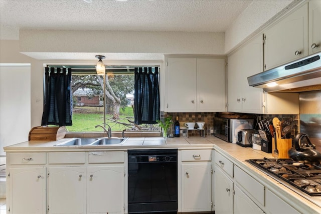 kitchen featuring under cabinet range hood, a sink, white cabinetry, appliances with stainless steel finishes, and tile counters