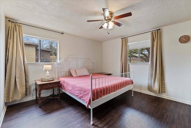 bedroom with a textured ceiling, multiple windows, wood finished floors, and baseboards