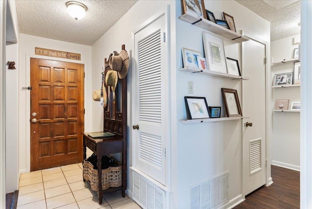 foyer with visible vents, a textured ceiling, and tile patterned floors