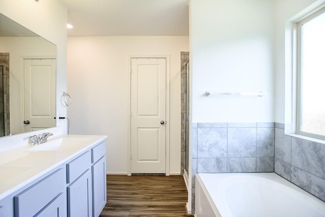 full bathroom featuring a stall shower, a garden tub, a sink, and wood finished floors