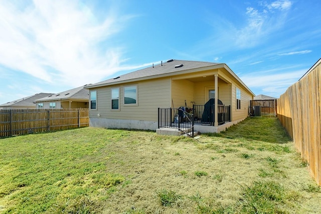 rear view of house featuring a fenced backyard and a yard