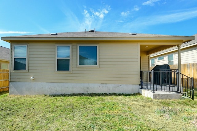 rear view of house with a yard and fence