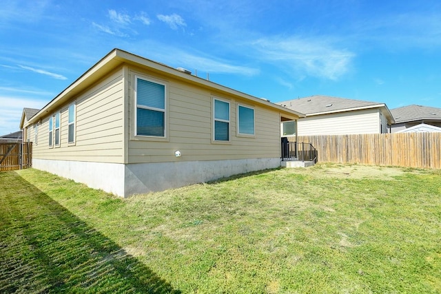 back of property with a lawn and fence