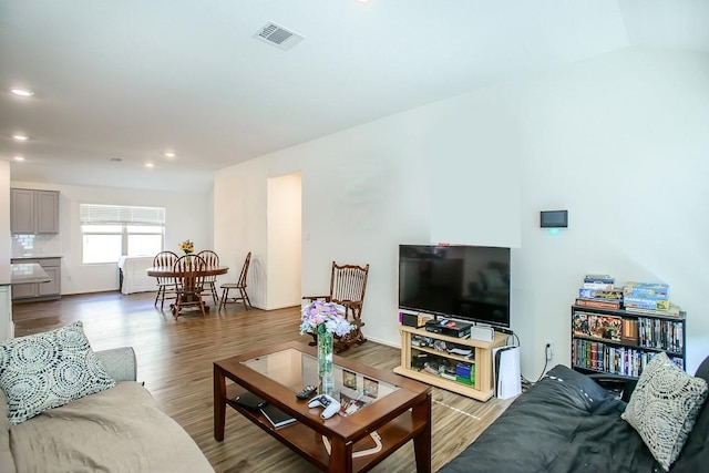 living area with wood finished floors, visible vents, and recessed lighting