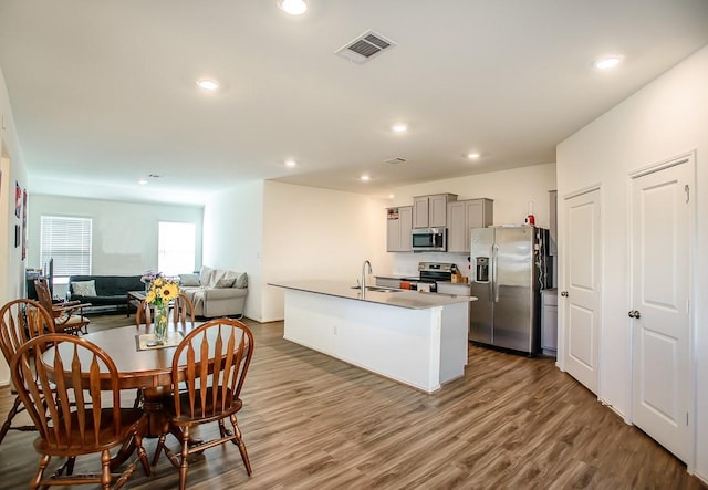 kitchen with visible vents, wood finished floors, gray cabinets, stainless steel appliances, and a sink