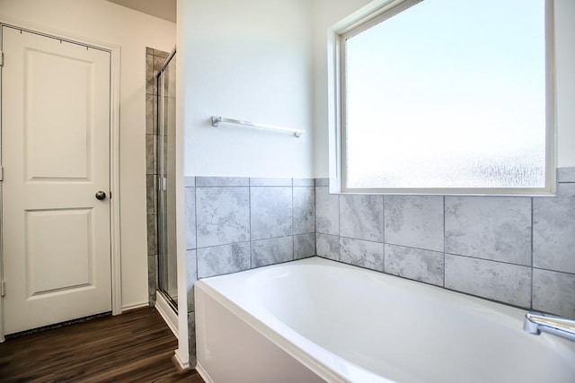 full bath with a stall shower, wood finished floors, plenty of natural light, and a bath