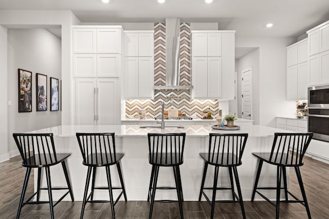 kitchen with a center island with sink, stainless steel appliances, recessed lighting, decorative backsplash, and dark wood-type flooring