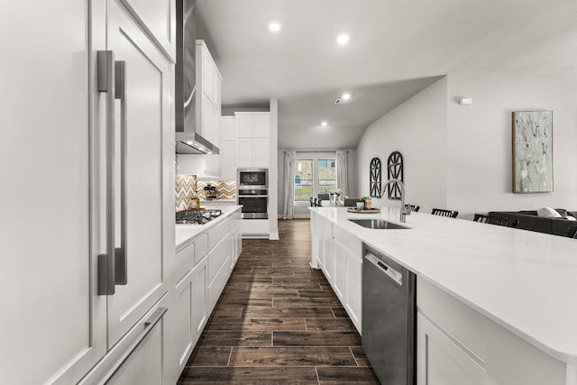 kitchen with stainless steel appliances, dark wood-type flooring, a sink, white cabinets, and decorative backsplash